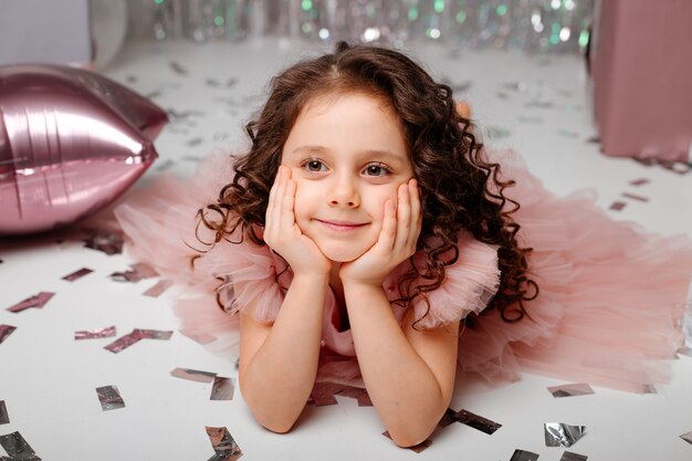 Foto niña en un vestido elegante con globos y confeti