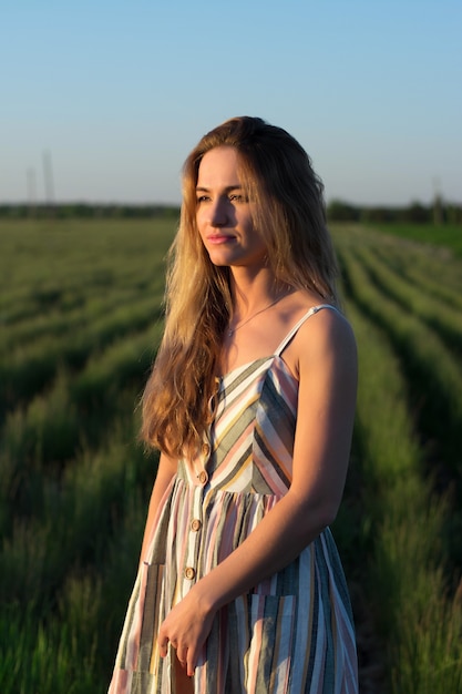 Una niña con un vestido ligero en un campo verde al atardecer