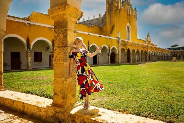 Una niña con un vestido multicolor se encuentra cerca de la Basílica de San Antonio de Padua Izamal México