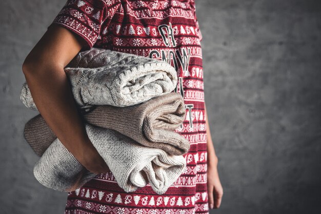 Foto una niña con un vestido de navidad tiene una pila de suéteres