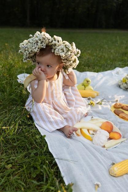 Niña en un vestido de rayas en un picnic en un parque de la ciudad.