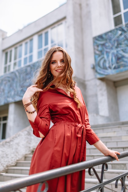 Una niña en un vestido rojo de pie en las escaleras