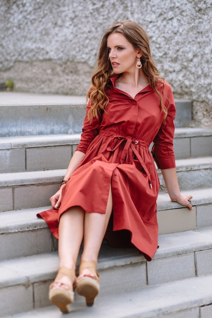 Una niña en un vestido rojo sentada en las escaleras