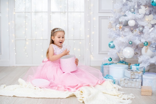 Niña con un vestido rosa abriendo una caja