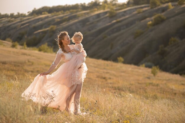 niña en un vestido rosa aireado sostiene a una niña en sus brazos