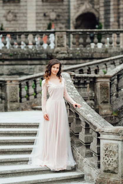 Una niña con un vestido rosa claro con el telón de fondo de un castillo de piedra polaco medieval