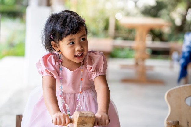 Una niña con un vestido rosa está jugando con un juguete de madera.