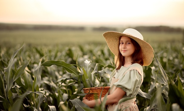 Niña con vestido y sombrero de pie en un campo de maíz