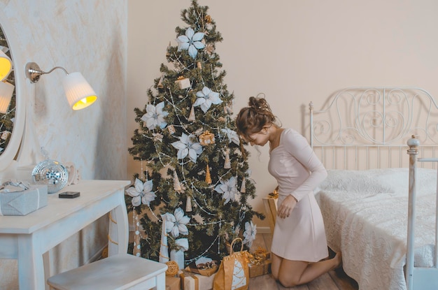 Una niña con un vestido de verano beige de fin de año analiza los regalos.