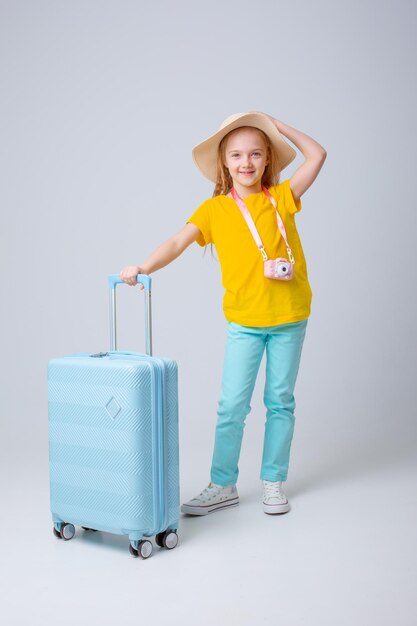 una niña viajera con una maleta en un fondo blanco
