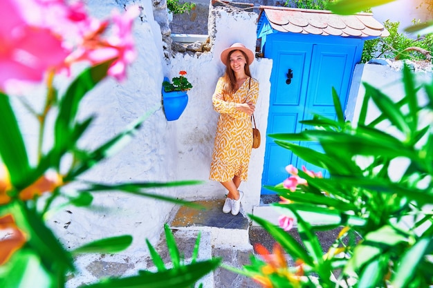 Niña viajera con vestido y sombrero camina por una antigua y hermosa calle con casas blancas y puertas azules en una ciudad europea