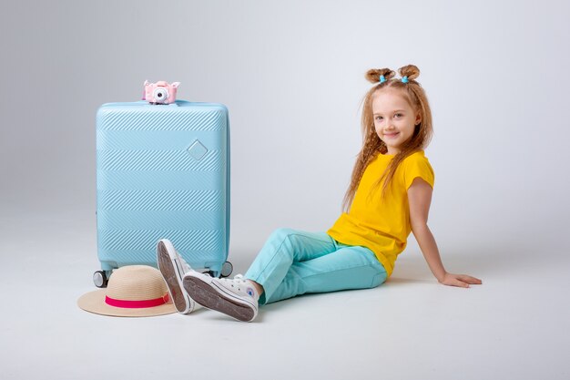 Niña con un viajero maleta sobre un fondo blanco.