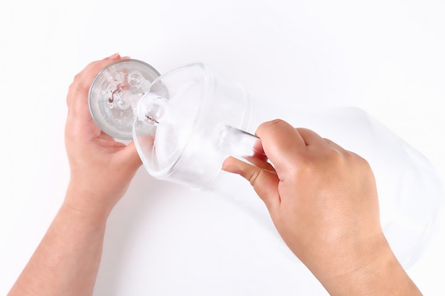 La niña vierte agua de una jarra en un vaso.