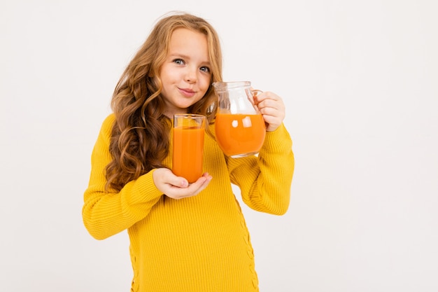 Niña vierte el jugo de zanahoria de una jarra en un vaso