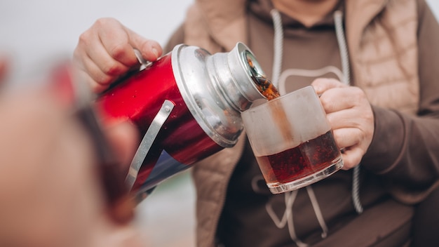 Foto una niña vierte té de un termo en una taza