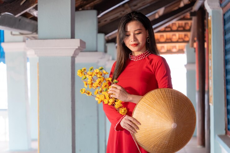 Foto niña vietnamita con vestido ao dai de pie en una casa tradicional de vietnam el texto en la foto significa mejores deseos de felicidad familiar prosperidad salud vacaciones de tet y año nuevo