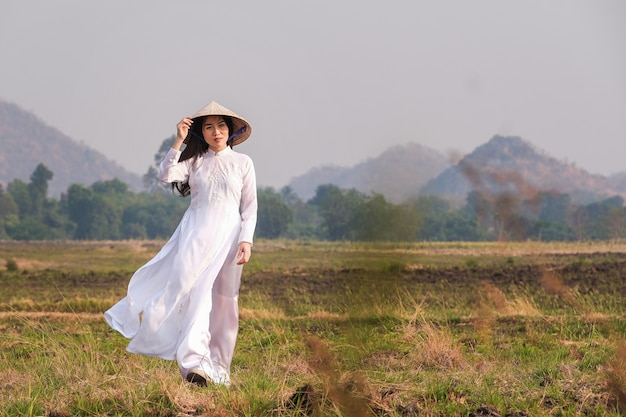 Niña vietnamita en vestido blanco con sombrero camina