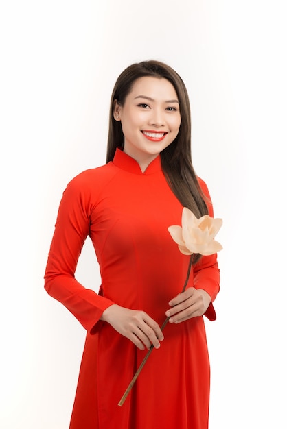 Niña vietnamita con un vestido rojo ao dai en la mano, flor de loto. Feliz, sonriente, cara