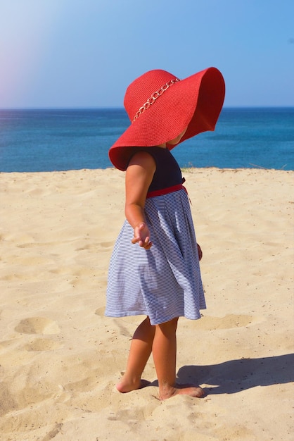 Niña viste sombrero rojo en la playa