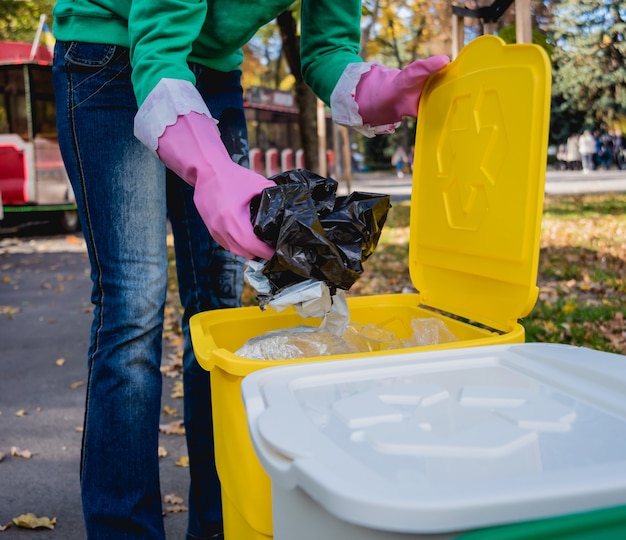 La niña voluntaria clasifica la basura en la calle del parque. Concepto de reciclaje.