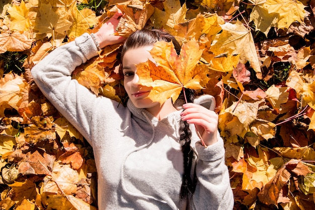 La niña yace en las hojas de otoño