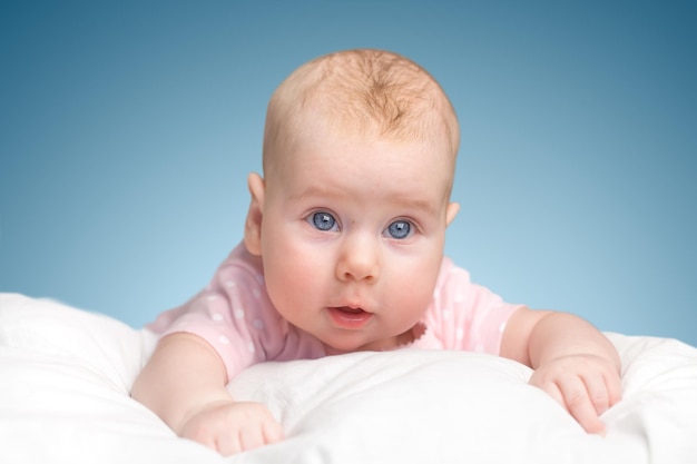 La niña yace sobre una almohada - nube. sobre un fondo azul