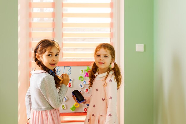 Las niñas de 6 años resuelven el problema matemático con la ayuda de dígitos magnéticos de plástico en la guardería. escuela montessori