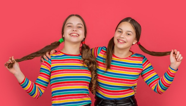 Niñas adolescentes felices abrazándose sobre fondo rosa