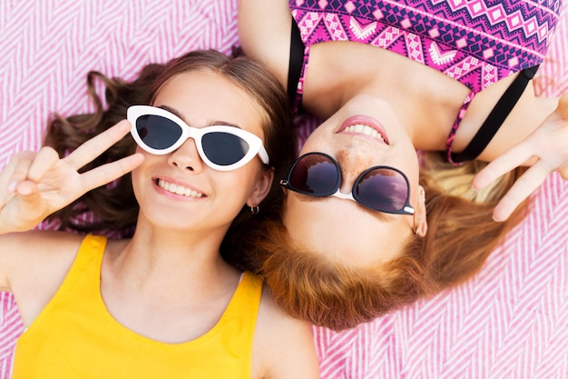 Foto niñas adolescentes con gafas de sol mostrando el signo de la paz