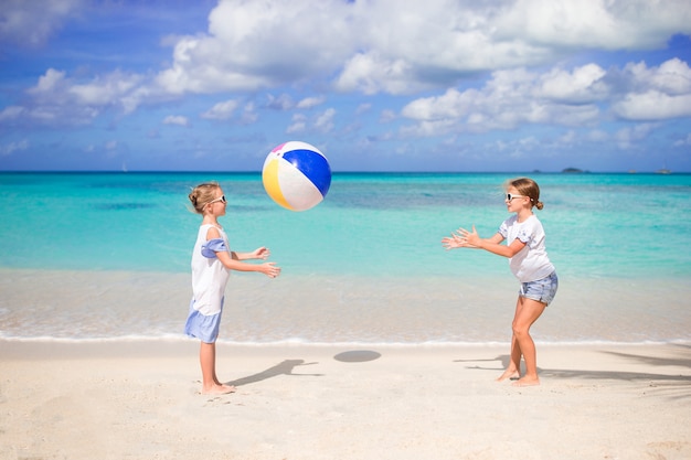 Niñas adorables jugando con la pelota en la playa