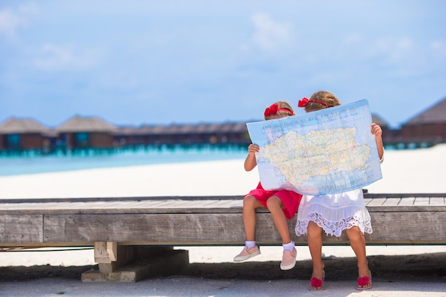 Niñas adorables con el mapa de la isla en la playa