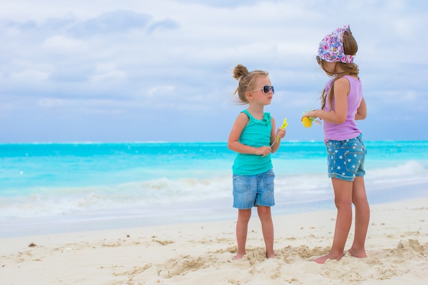 Niñas adorables en la playa tropical blanca