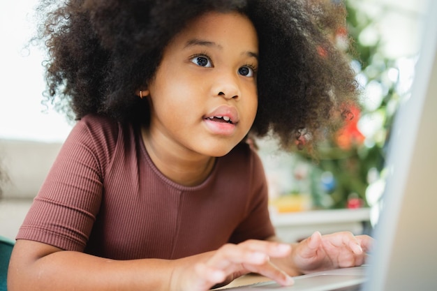 Las niñas afroamericanas se divierten trabajando juntas mientras estudian en línea usando computadoras en casa