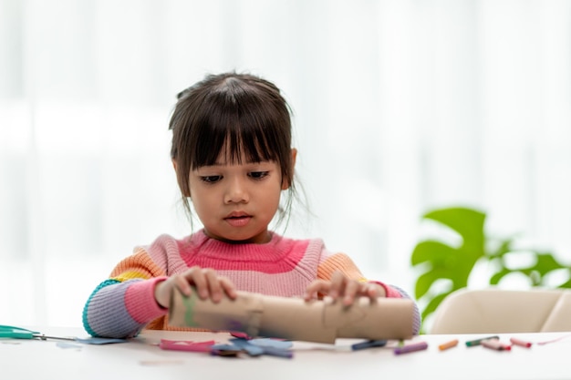 Las niñas asiáticas están haciendo binoculares con núcleo de papel tisú Reutilizar productos de desecho Idea de juguete hecho a medida Enfoque suave