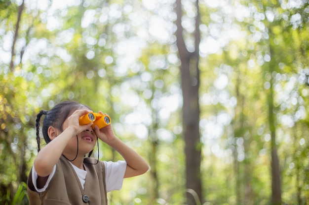 Niñas asiáticas felices mirando hacia adelante y niños sonrientes con los binoculares en el parque Concepto de viaje y aventura Vacaciones en libertad