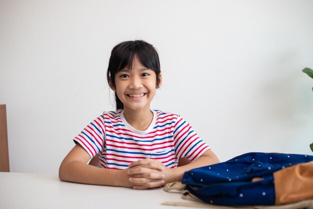 Niñas asiáticas lindas de la escuela primaria empacando sus mochilas escolares preparándose para el primer día de clases La rutina escolar matutina para el día en la vida preparándose