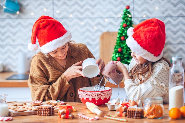 Niñas cocinando pan de jengibre de Navidad. Hornear y cocinar con niños para Navidad en casa.