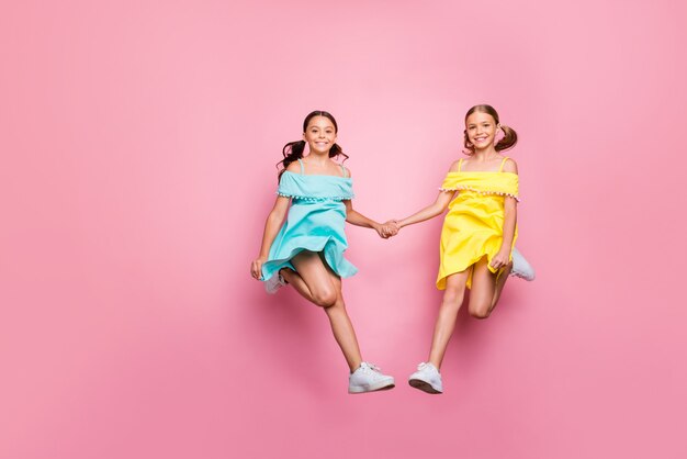 Niñas con coletas posando contra la pared rosa