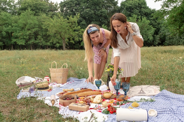 Niñas colocando comida de picnic en una manta de picnic a cuadros