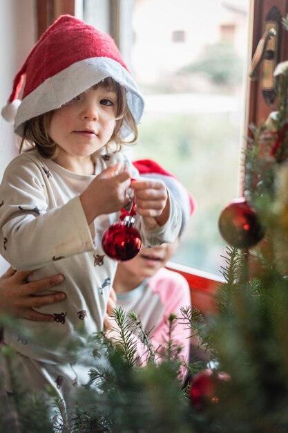 Niñas decorando el árbol de Navidad en casa con el apoyo de la hermana