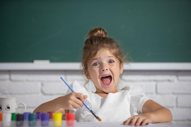 Niñas dibujando imágenes coloridas con lápices de colores en el aula de la escuela pintando pintura para niños