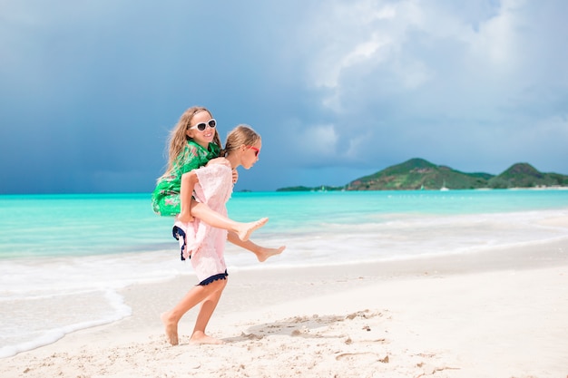 Las niñas divertidas y felices se divierten mucho jugando en la playa tropical.