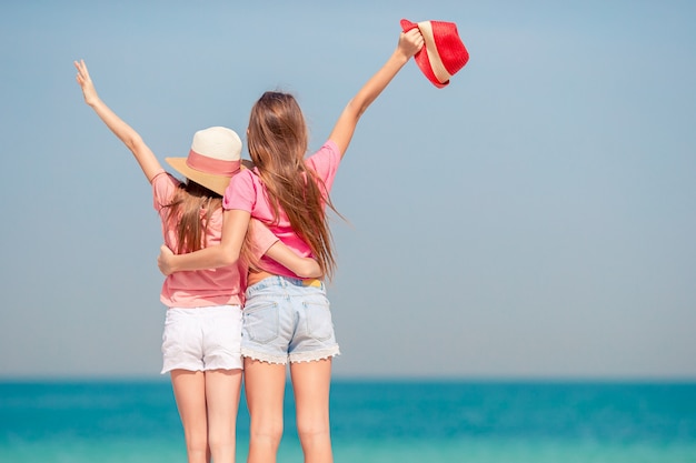 Las niñas divertidas y felices se divierten mucho en la playa tropical jugando juntas. Día soleado con lluvia en el mar