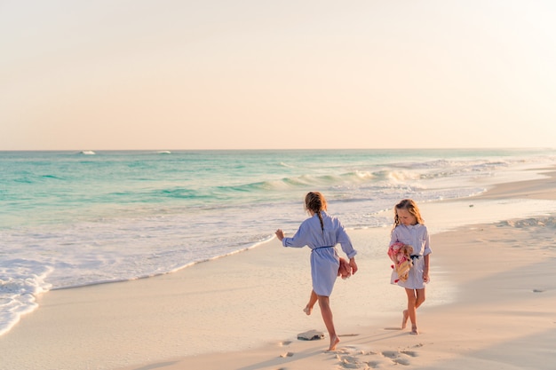 Niñas divirtiéndose en la playa tropical jugando juntos en aguas poco profundas