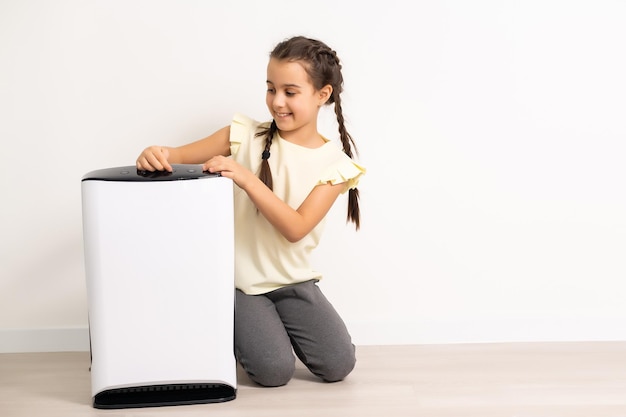 Las niñas en edad escolar primaria disfrutan de la comodidad en casa con una caja blanca de humidificador de aire, atención médica y dispositivos modernos.