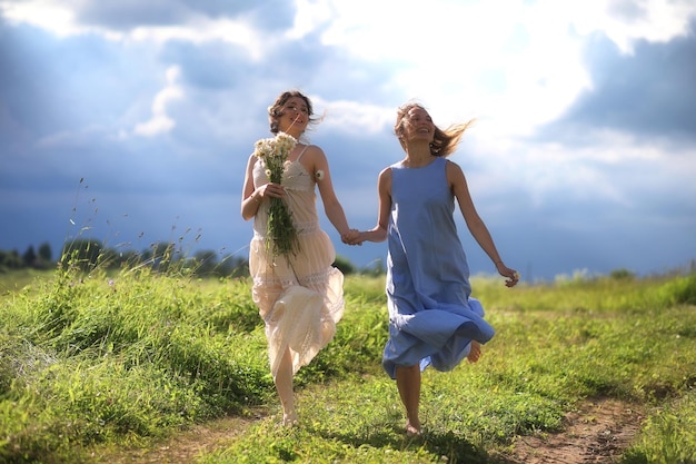 Las niñas están caminando en el campo antes de la lluvia.