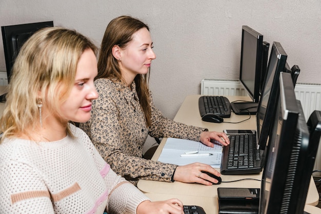 Las niñas están estudiando photoshop en una clase de computación.