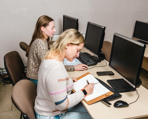 Las niñas están estudiando photoshop en una clase de computación.