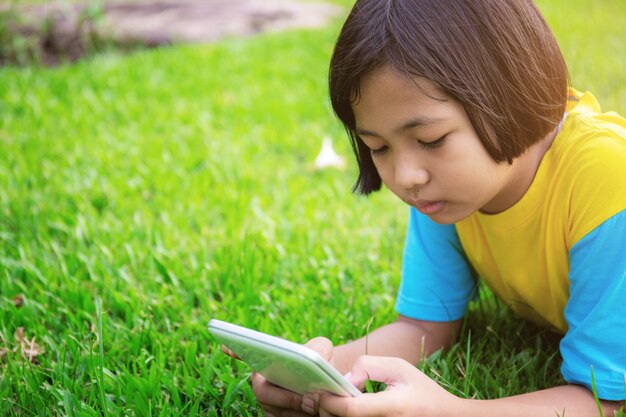 Las niñas están utilizando tabletas en el césped.