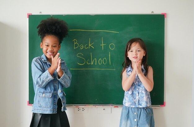 Niñas felices contra la pizarra con regreso a la escuela